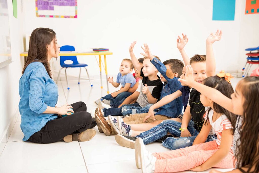 Preschool Students Raising Hand In Playschool Class